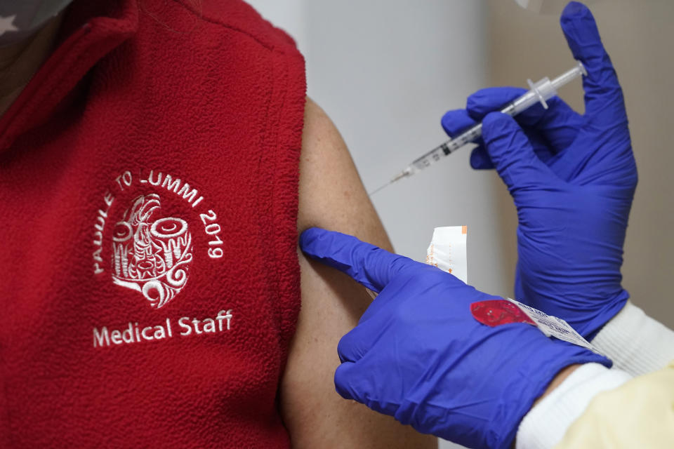 Medical worker Melissa Fitzgerald receives a COVID-19 vaccination Thursday, Dec. 17, 2020, at the Chinook Clinic on the Lummi Reservation, near Bellingham, Wash. The Native American tribe began rationing its first 300 doses of vaccine as it fights surging cases with a shelter-in-place order. (AP Photo/Elaine Thompson)