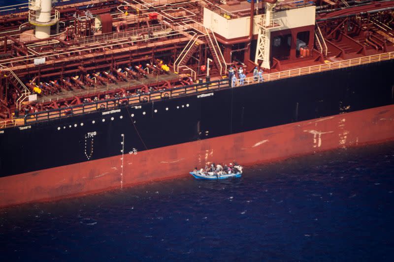 Migrants sit in a boat alongside the Maersk Etienne tanker off the coast of Malta