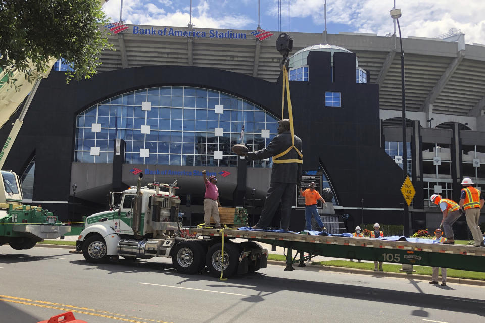 A statue of former Carolina Panthers owner Jerry Richardson is lowered onto a truck after it was removed from in front of the team's stadium in Charlotte, N.C., Wednesday, June 10, 2020. “We were aware of the most recent conversation surrounding the Jerry Richardson statue and are concerned there may be attempts to take it down," the team said in a statement. "We are moving the statue in the interest of public safety.” (AP Photo/Steve Reed)