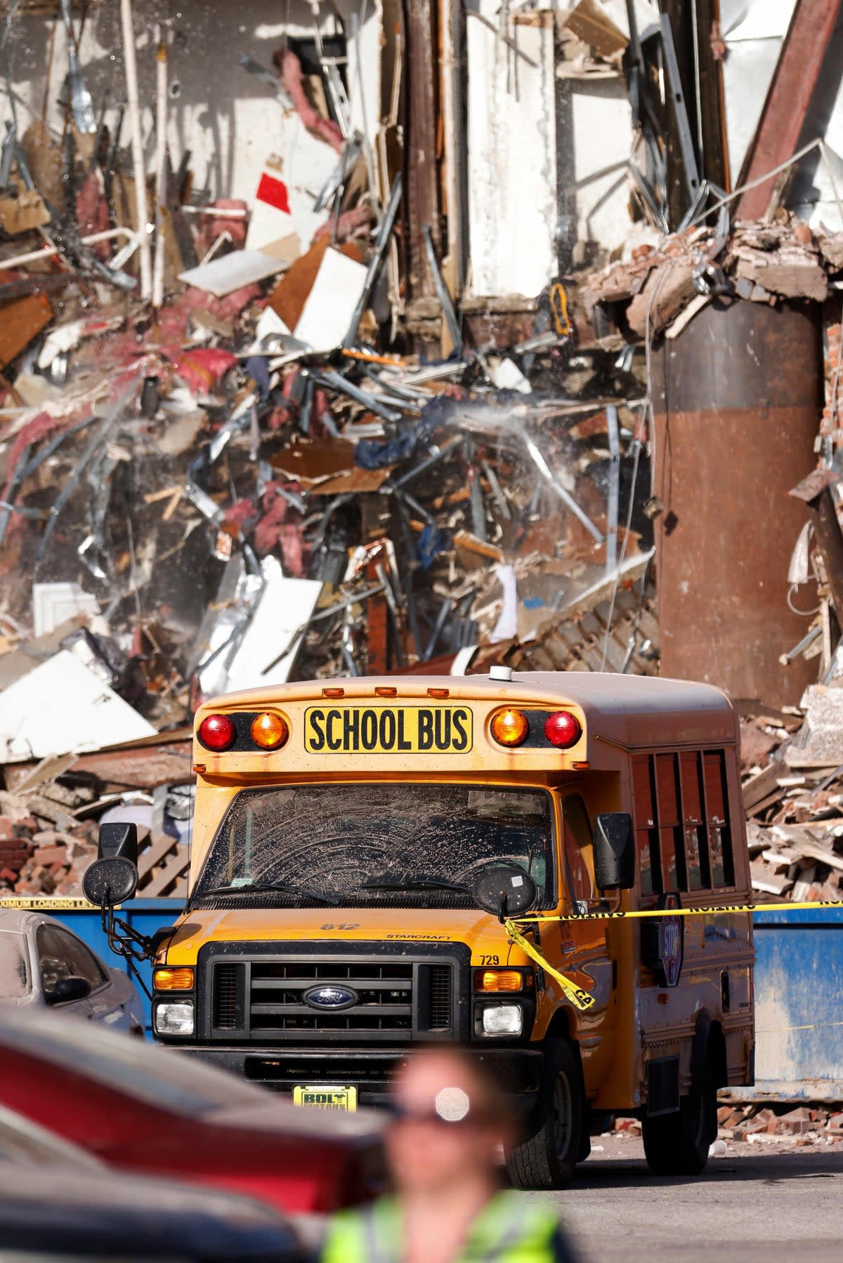 A school bus drives past the wreckage after the building collapse on Sunday (Quad City Times)