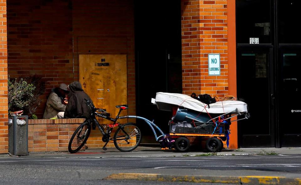 A pair of homeless men sit \with their belongings in the entryway of a vacant building on Vista Way in Kennewick on April 6, 2023