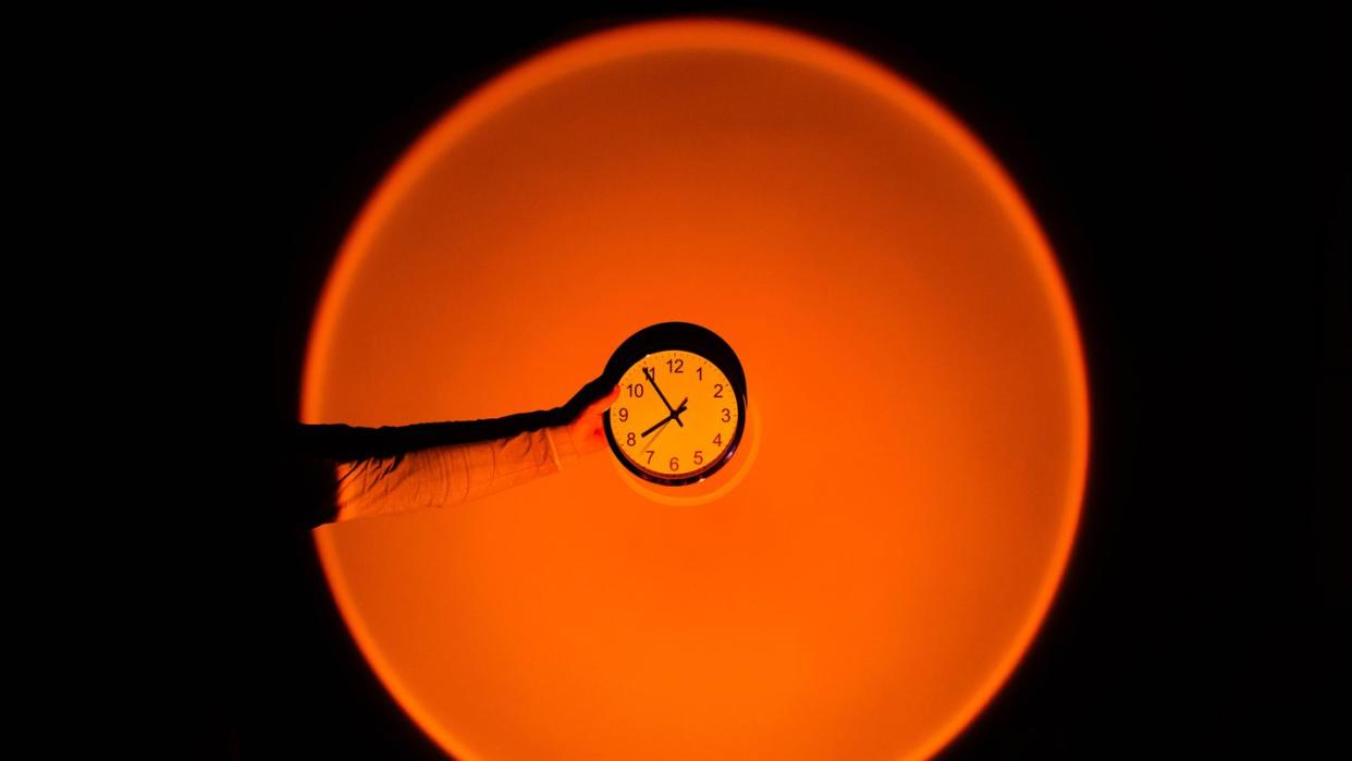 holding wall clock against big sunset sun light effect