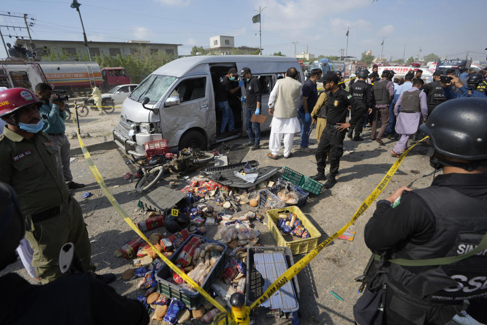 Pakistani investigators examine a damaged van at the site of a suicide attack in Karachi, Pakistan, Friday, April 19, 2024. A suicide bomber detonated his explosive-laden vest near a van carrying Japanese autoworkers, who narrowly escaped the attack Friday that wounded three bystanders in Pakistan's port city of Karachi, police said. (AP Photo/Fareed Khan)