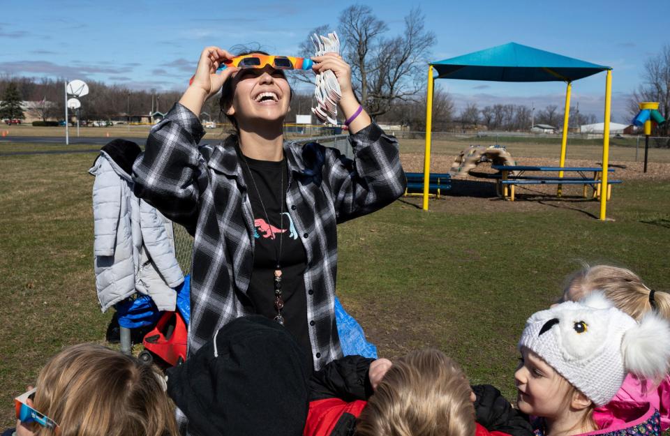 Madilyn Hafner, a Great Start Readiness Program preschool teacher from Mason Central Elementary, wears solar eclipse glasses to look up at the sun with her class during an activity in Erie on Thursday, March 7, 2024.