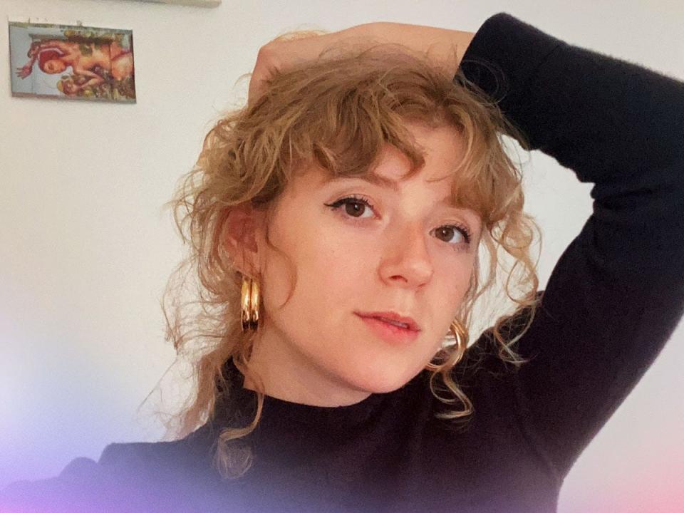 headshot of woman staring into camera with her hand over her head.