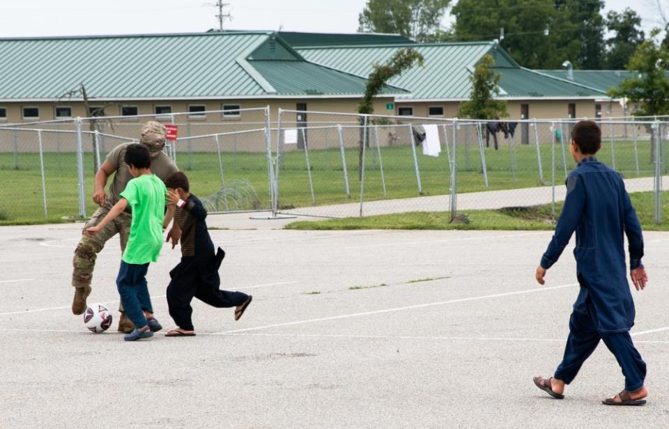 A soldier plays soccer with children at Indiana's Camp Atterbury on Sept. 4.