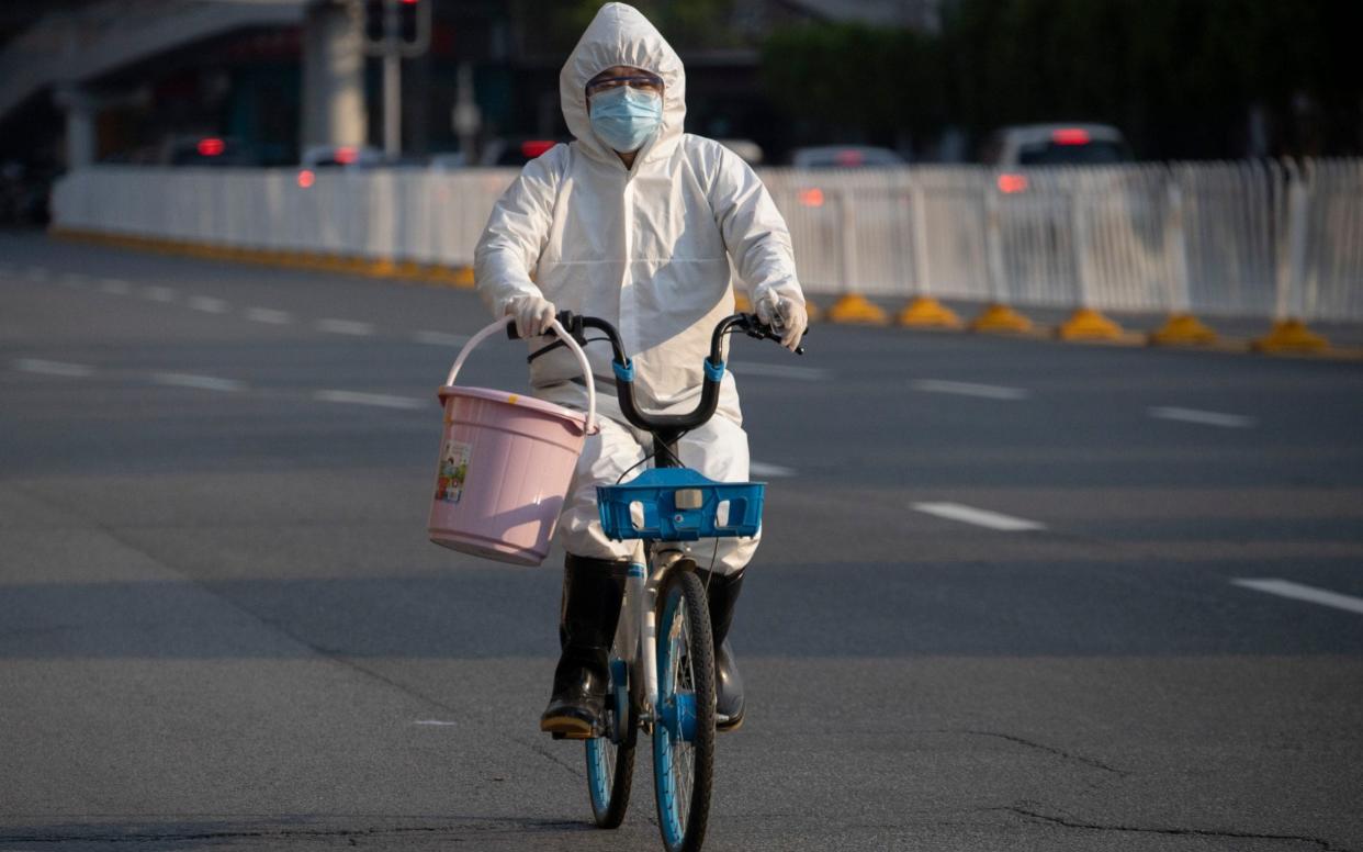 A resident in mask and suit in April in Wuhan in China, where the coronavirus originated. - Ng Han Guan /AP