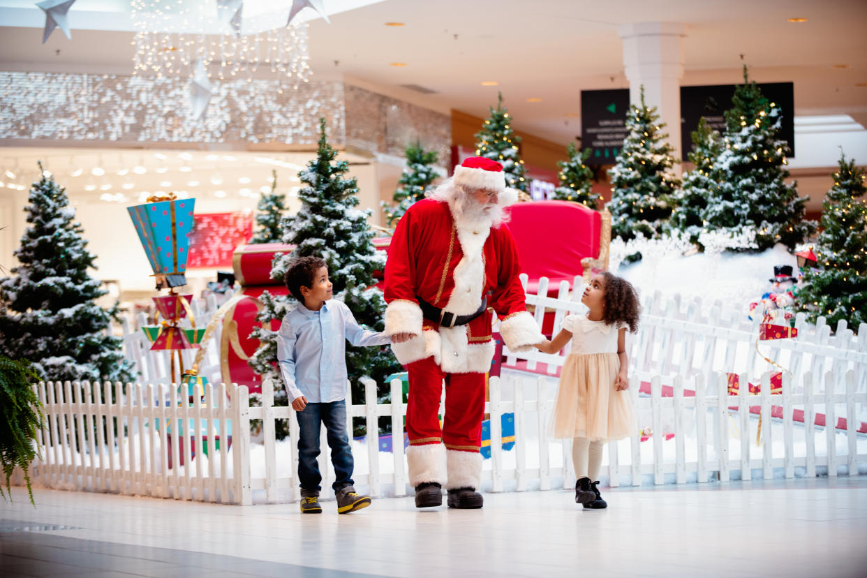 Multi-Ethnic family shops at Shopping Mall during Christmas Time with Santa Claus. Santa Claus and children are walking hand by hand. Photo was taken in Quebec Canada.