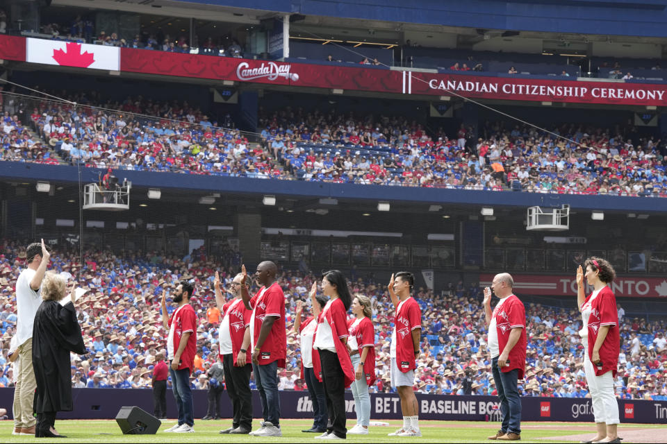 People take part in a Canada Day citizenship ceremony before the start of a baseball game between the Toronto Blue Jays and the Boston Red Sox in Toronto, Saturday, July 1, 2023. (Frank Gunn/The Canadian Press via AP)