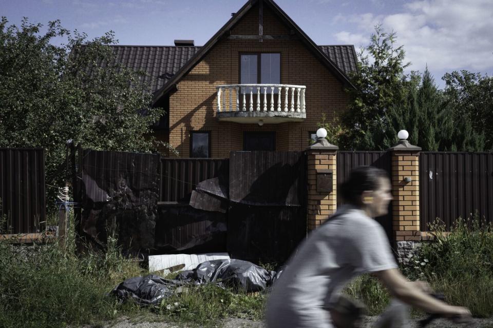 A woman on a bicycle passes a brown home