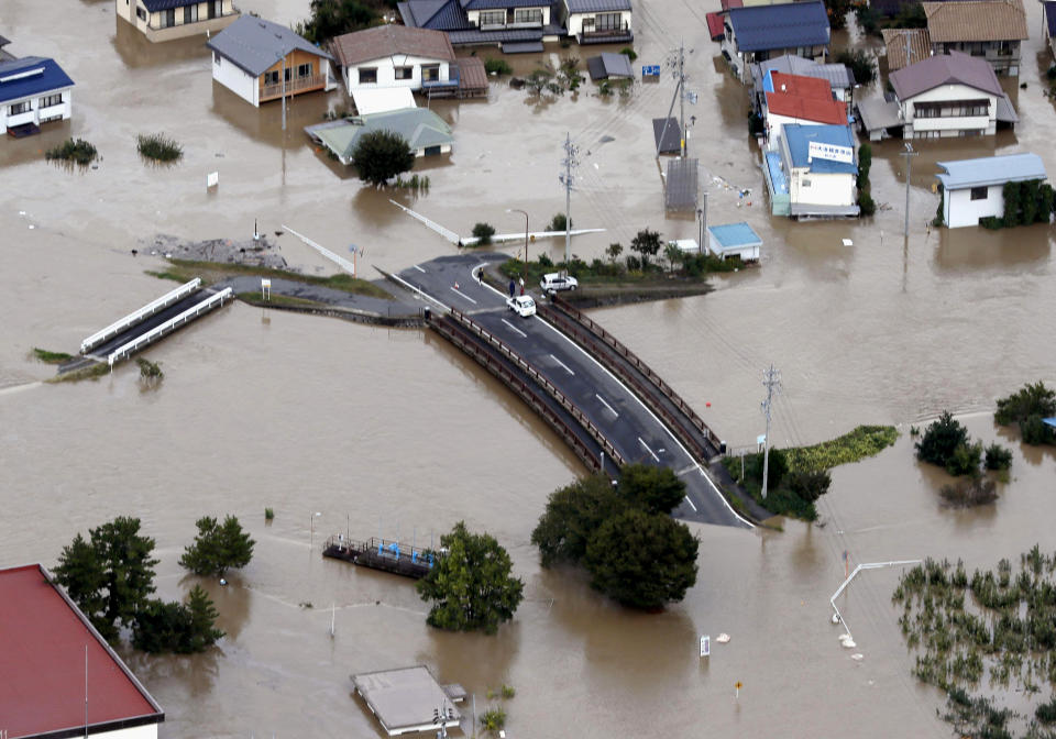 In this Sunday, Oct. 13, 2019, file photo, cars are stranded on a road as the city is submerged in muddy waters after an embankment of the Chikuma River broke, in Nagano, central Japan. Rescue efforts for people stranded in flooded areas are in full force after a powerful typhoon dashed heavy rainfall and winds through a widespread area of Japan, including Tokyo. (Yohei Kanasashi/Kyodo News via AP, File)
