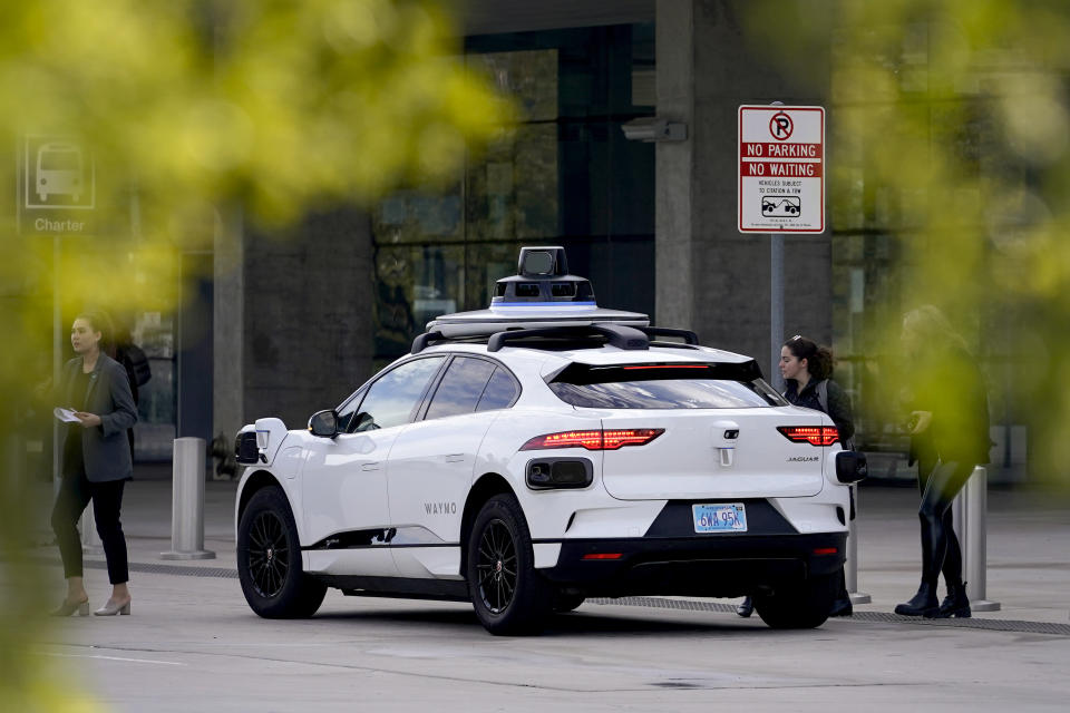 FILE - A Waymo self-driving vehicle sits curbside on Dec. 16, 2022, at the Sky Harbor International Airport Sky Train facility in Phoenix. Self-driving car pioneer Waymo announced Thursday, May 4, 2023, that its robotaxis will be able to carry passengers through most of the Phoenix area for the first time. (AP Photo/Matt York, File)
