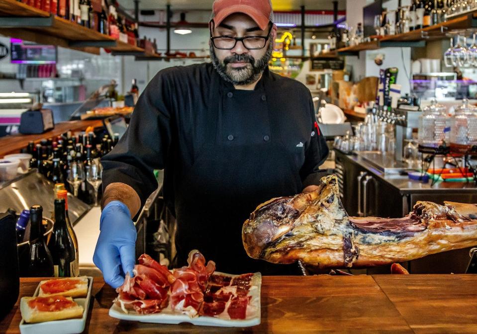 Chef Neil Herekar prepares the Jamón Jamón Jamón plate (a sampling of Ibérico, culatello and country hams) at the Jamón Jamón tapas bar inside the Delray Beach Market food hall.