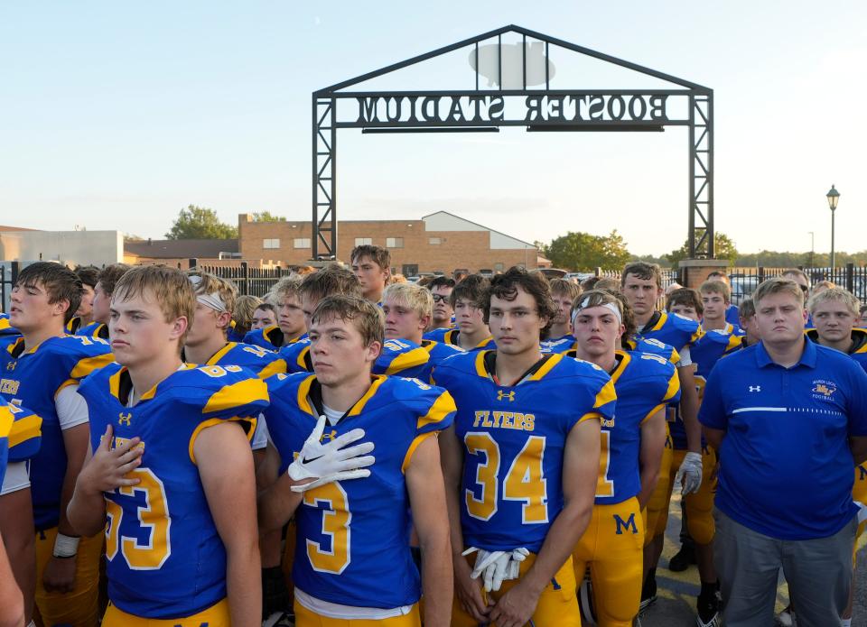 Marion Local football players stand for the national anthem before a Sept. 22 game against Versailles.