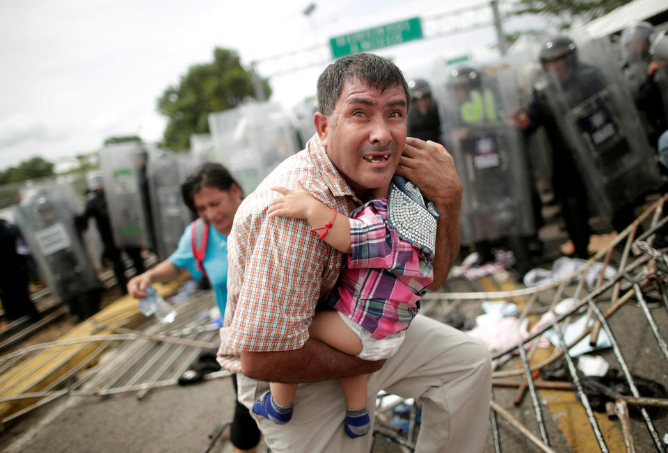 <p>A Honduran migrant protects his child after fellow migrants, part of a caravan trying to reach the U.S., stormed a border checkpoint in Guatemala, in Ciudad Hidalgo, Mexico, Oct. 19, 2018. (Photo: Ueslei Marcelino/Reuters) </p>