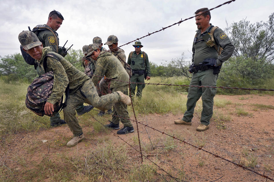 Migrantes detenidos por la Patrulla Fronteriza atraviesan un cerco de alambres de púas cerca de Sasabe (Arizona) el 8 de septiembre del 2022. Muchos migrantes mueren en el desierto tratando de cruzar ilegalmente de México a EEUU. (AP Photo/Matt York)