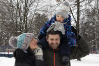 In this photo taken on Saturday, Feb. 16, 2019, Ilya Zhegulev, a journalist for the Latvia-based Russian website Meduza, his son Ivan and his wife Katya pose for a photo during a walk to the playground in snowy Moscow. Last year, Zhegulev sold two cars to finance a trip to California for him and his wife so she could give birth to their son and acquire a U.S. passport for their son. (AP Photo/Iuliia Stashevska)