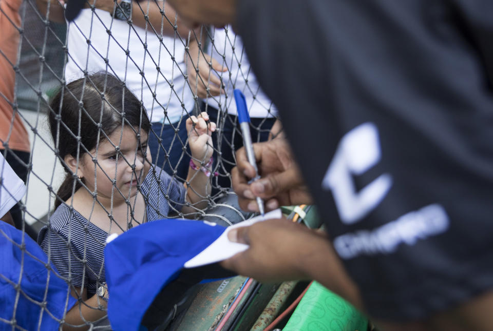 A child watches as retired Dominican professional Major League pitcher Octavio Dotel autographs her baseball cap during the Day of Legends event at the Quisqueya Stadium, in Santo Domingo, Dominican Republic, Sunday, Dec. 8, 2019. (AP Photo/Tatiana Fernandez)