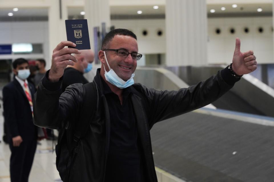 An Israeli passenger from a flyDubai flight from Tel Aviv, Israel, waves his Israeli passport on arrival at Dubai International Airport's Terminal 3 in Dubai, United Arab Emirates, Thursday, Nov. 26, 2020. The low-cost carrier flyDubai began regular flights to Tel Aviv on Thursday, the latest sign of the normalization deal between the UAE and Israel. (AP Photo/Jon Gambrell)