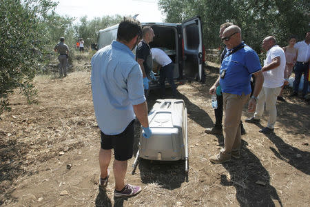 Rescuers stand next to a coffin containing a victim at the site where two passenger trains collided in the middle of an olive grove in the southern village of Corato, near Bari, Italy July 12, 2016. REUTERS/Stringer