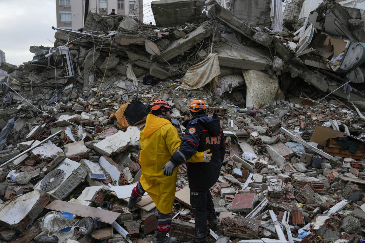 Emergency team members pause for a moment as they search for people in a destroyed building in Adana, Turkey (Khalil Hamra / AP)