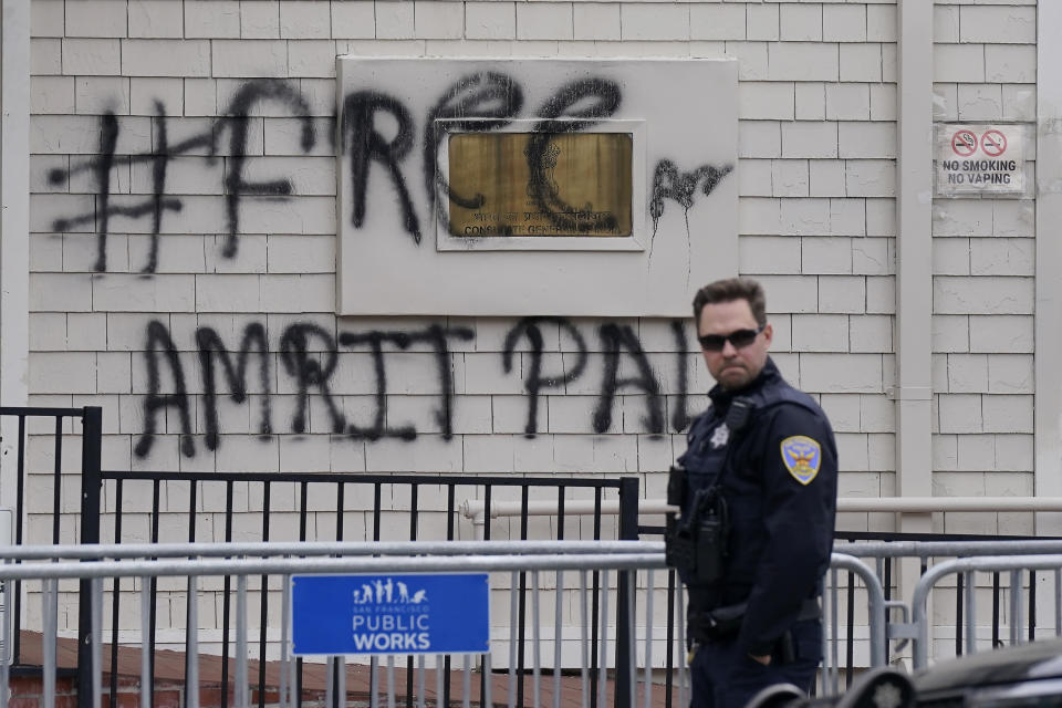 A San Francisco Police Officer stands outside of the entrance to the Consulate General of India in San Francisco, Monday, March 20, 2023. San Francisco police had erected barriers and parked a vehicle nearby as people protested outside the Consulate General of India to protest the capture of Amritpal Singh. (AP Photo/Jeff Chiu)