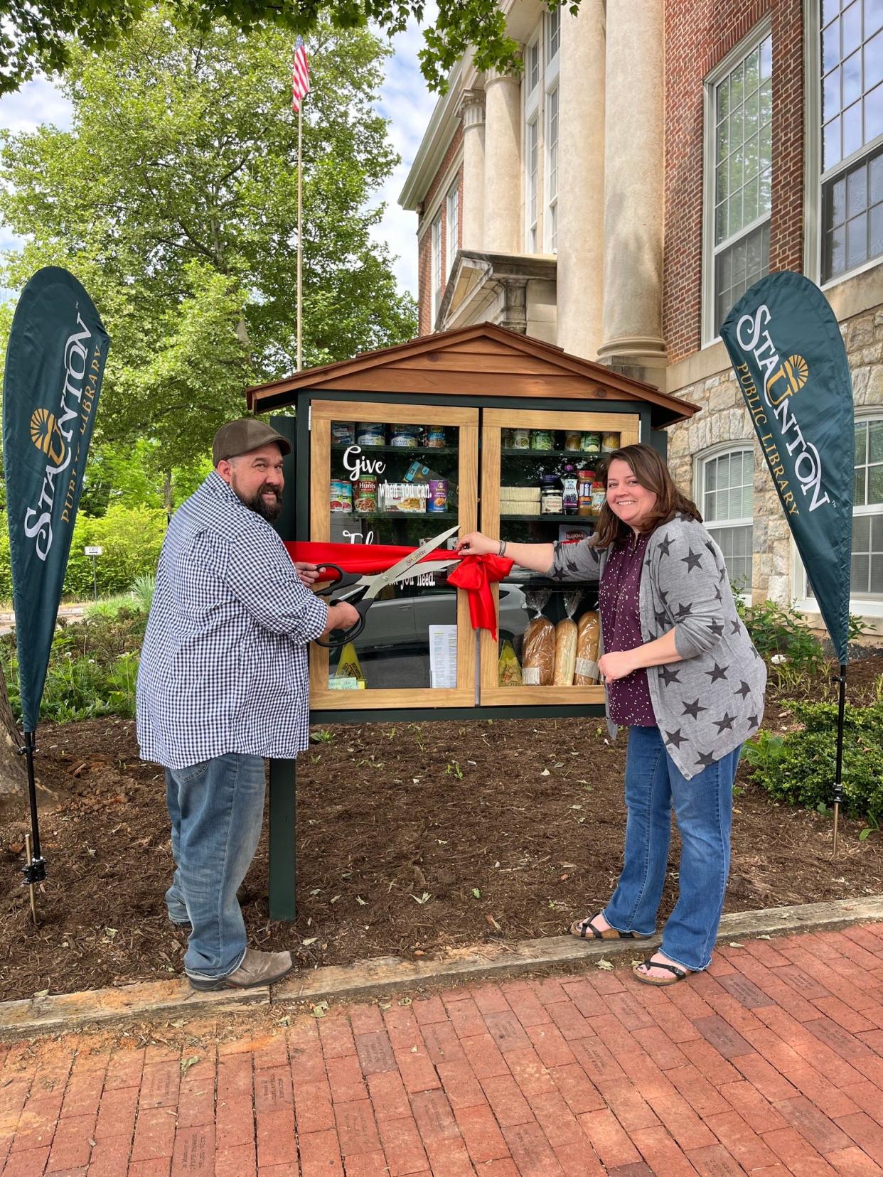 Neighbor Bridge representatives hold oversized scissors as they cut the ribbon to open the pantry.