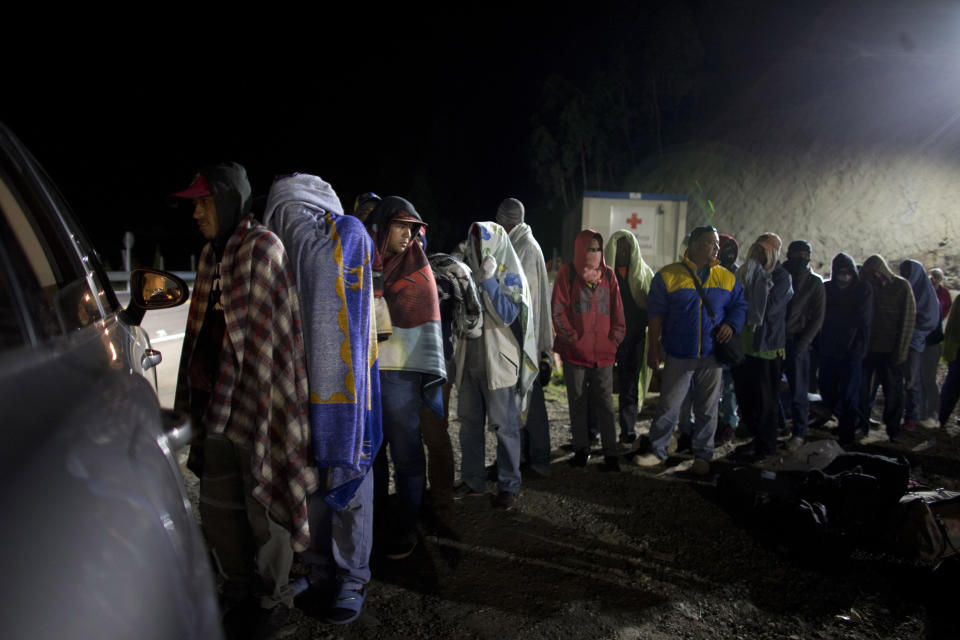 FILE - In this Aug. 31, 2018 file photo, Venezuelan migrants line up for free bread and coffee, donated by a Colombian family from their car, at a gas station in Pamplona, Colombia. A record 71 million people have been displaced worldwide from war, persecution and other violence, the U.N. refugee agency said Wednesday, June 18, 2019, an increase of more than 2 million from last year and an overall total that would amount to the world's 20th most populous country. Amid runaway inflation and political turmoil at home, Venezuelans for the first time accounted for the largest number of new asylum-seekers in 2018, with more than 340,000, or more than one in five worldwide last year. (AP Photo/Ariana Cubillos)