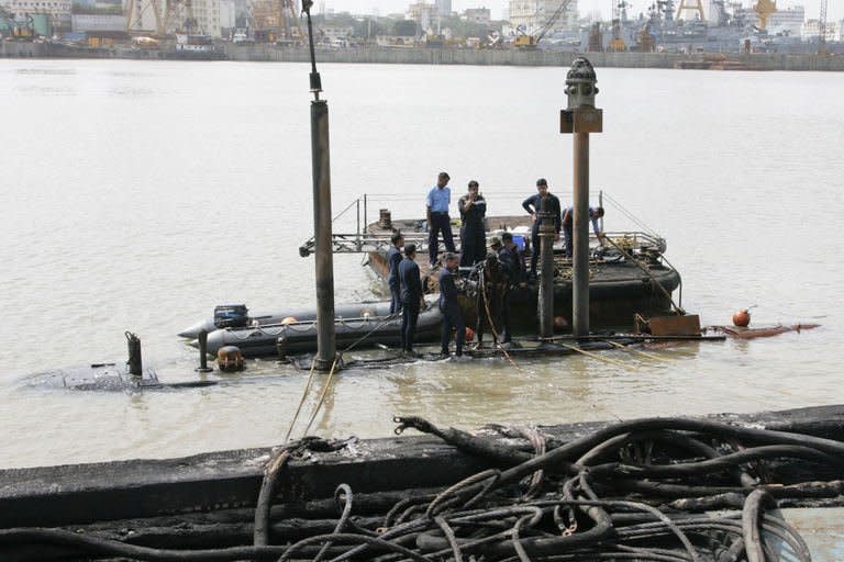Indian Navy divers inspect the conning tower of the stricken INS Sindhurakshak, after the submarine sank following an explosion at the naval dockyard in Mumbai, on August 14, 2013. Indian divers and engineers have struggled to refloat a submarine that exploded with 18 crewmen on board, as the prime minister voiced "deep regret" at the blast which is feared to have left no survivors