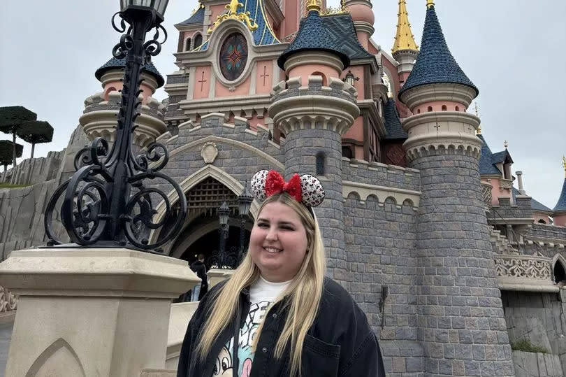A girl stood in front of the pink Disneyland Paris castle