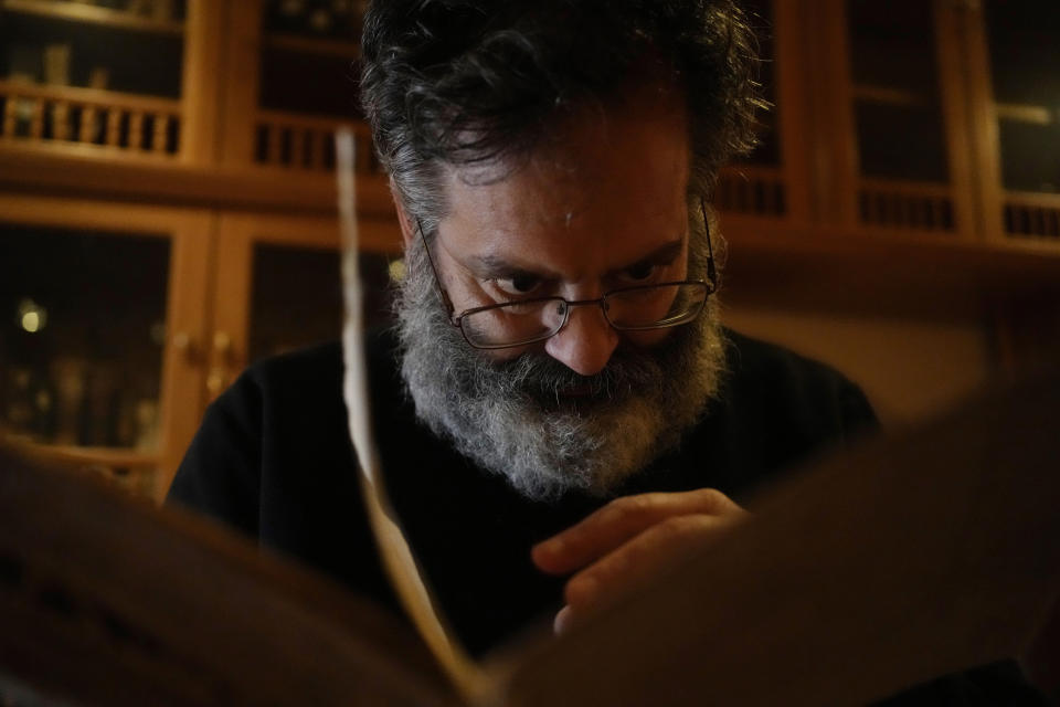 Byzantine scholar Yiannis Niehoff-Panagiotidis reads a manuscript at the library of Pantokrator Monastery in the Mount Athos, northern Greece, on Thursday, Oct. 13, 2022. Deep inside a medieval fortified monastery in the Mount Athos monastic community, researchers are for the first time tapping a virtually unknown treasure: thousands of Ottoman-era manuscripts that include the oldest of their kind in the world. (AP Photo/Thanassis Stavrakis)