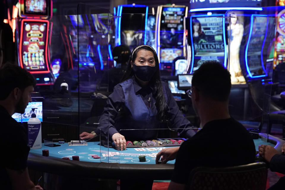 People play blackjack at the reopening of the Bellagio hotel and casino Thursday, June 4, 2020, in Las Vegas. Casinos in Nevada were allowed to reopen on Thursday for the first time after temporary closures as a precaution against the coronavirus. (AP Photo/John Locher)
