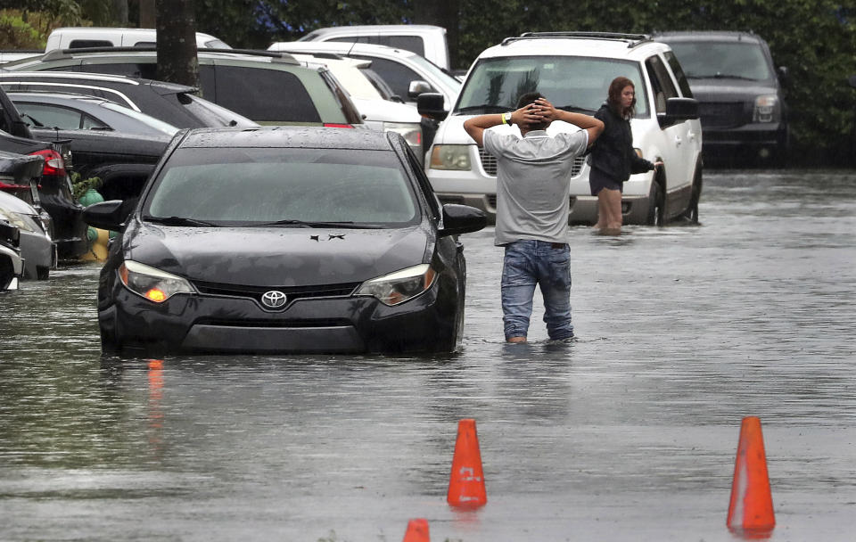 A driver climbs out of his stalled car after he tried to move it to higher ground from the flooded parking lot at the Beachwalk at Sheridan Apartments in Dania Beach, Fla., on Saturday, June 4, 2022. (Mike Stocker/South Florida Sun-Sentinel via AP)