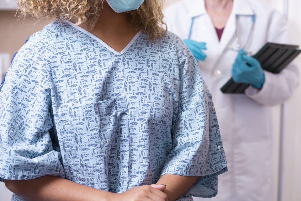 Young African American woman prepares for a breast exam, mammogram from her gynecologist doctor at hospital or clinic.