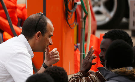 A police immigration officer talks to migrants after they disembarked from an Armed Forces of Malta patrol boat at its base in Marsamxett Harbour, Valletta, Malta May 25, 2019. REUTERS/Darrin Zammit Lupi