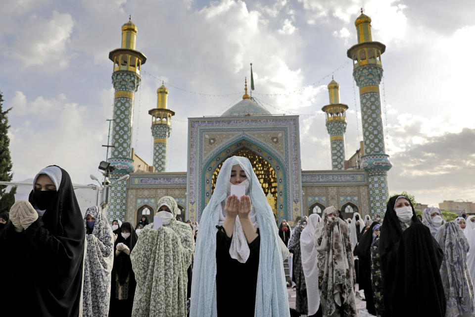 Worshippers wearing protective face masks offer Eid al-Fitr prayers outside a shrine to help prevent the spread of the coronavirus, in Tehran, Iran, Sunday, May 24, 2020. Muslims worldwide celebrate one of their biggest holidays under the long shadow of the coronavirus, with millions confined to their homes and others gripped by economic concerns during what is usually a festive time of shopping and celebration. (AP Photo/Ebrahim Noroozi)
