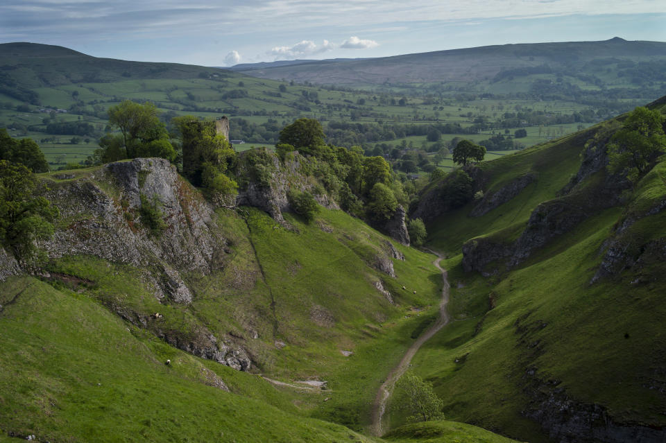 CASTLETON, ENGLAND - MAY 29: A view from Cave Dale across the Peak District with Peveril Castle to the left on the morning of 'Castleton Garland Day' on May 29, 2019 in Castleton, England. The first records of Garland day date back to the 1700's and though it's true origins are not fully understood it is believed to be an ancient fertility rite with Celtic connections. The celebration also incorporates more recent elements of 'Oak Apple Day' which falls on May 29th, and celebrates the restoration of the monarchy in 1660. The garland is a framework of cut flowers which is prepared on the day by villagers before being placed on the head of the 'King', and paraded around the town on horseback with his 'Consort', also on horseback, dressed in Stuart costume. (Photo by Dan Kitwood/Getty Images)