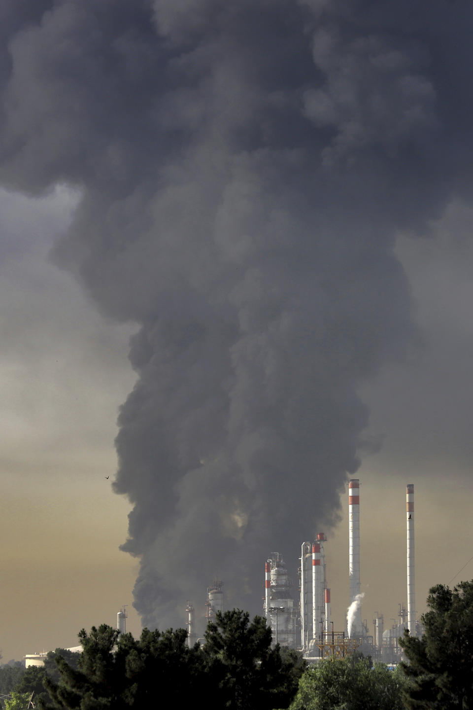 Huge plumes of smoke rise up from a main oil refinery south of Tehran, Iran, Thursday, June 3, 2021. A massive fire broke out Wednesday night at the oil refinery serving Iran's capital, sending thick plumes of black smoke over Tehran. (AP Photo/Ebrahim Noroozi)