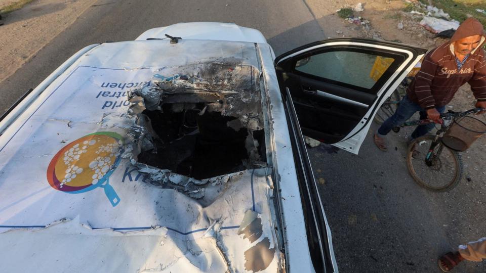 PHOTO: A Palestinian man rides a bicycle past a damaged vehicle where employees from the World Central Kitchen were killed in an Israeli airstrike in Deir Al-Balah, in the central Gaza Strip, Apr. 2, 2024.  (Ahmed Zakot/Reuters)