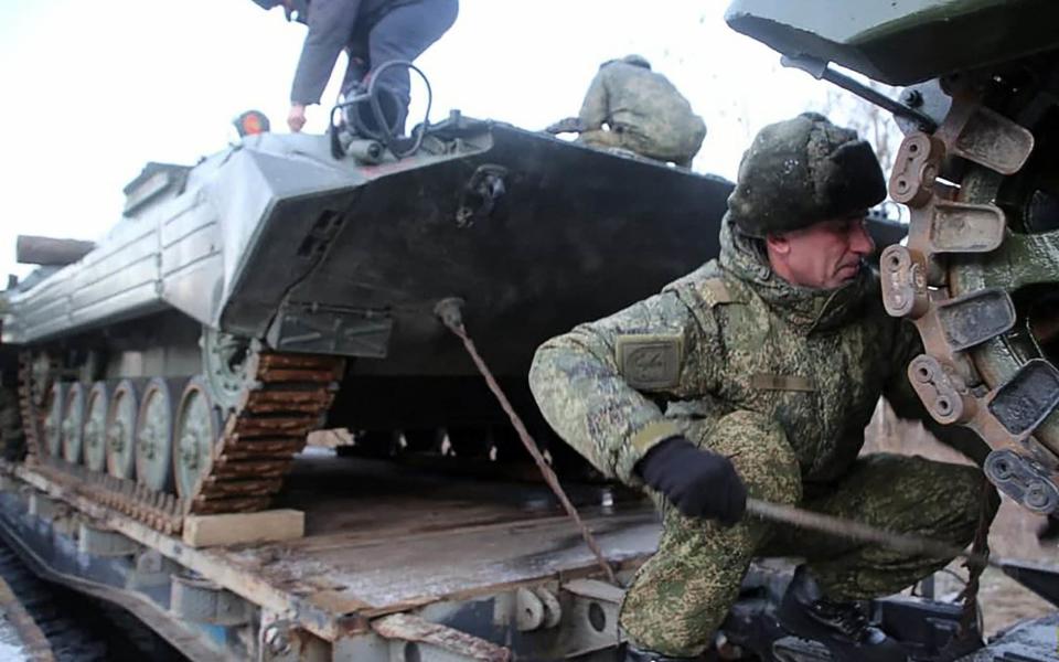 Russian servicemen preparing military vehicles to unload from a troop train for the joint drills in Belarus - AFP