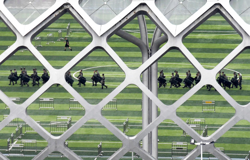 This Friday, Aug. 16, 2019, photo shows members of China's paramilitary People's Armed Police, in military fatigues, are seen at Shenzhen Bay Stadium in Shenzhen, China. Chinese police marched and practiced crowd control tactics at the sports complex in Shenzhen across from Hong Kong on Friday, in what some interpreted as a threat against pro-democracy protesters in the semiautonomous territory.(Madoka Ikegami/Kyodo News via AP)