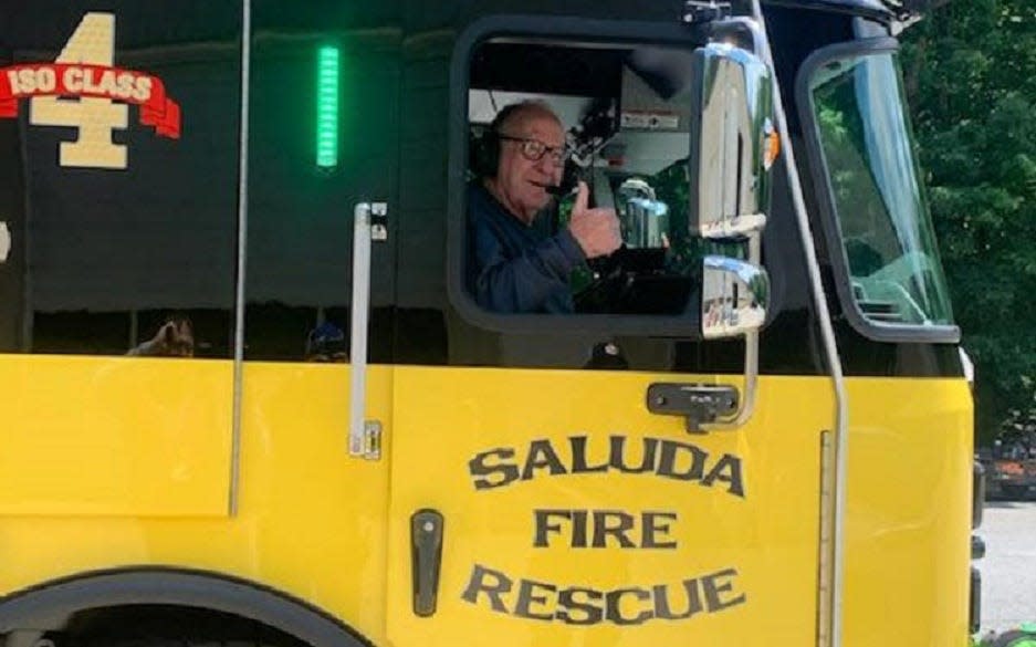 Longtime Saluda Fire Department firefighter Hop Foster gives a thumbs up as he rides in the fire engine.
