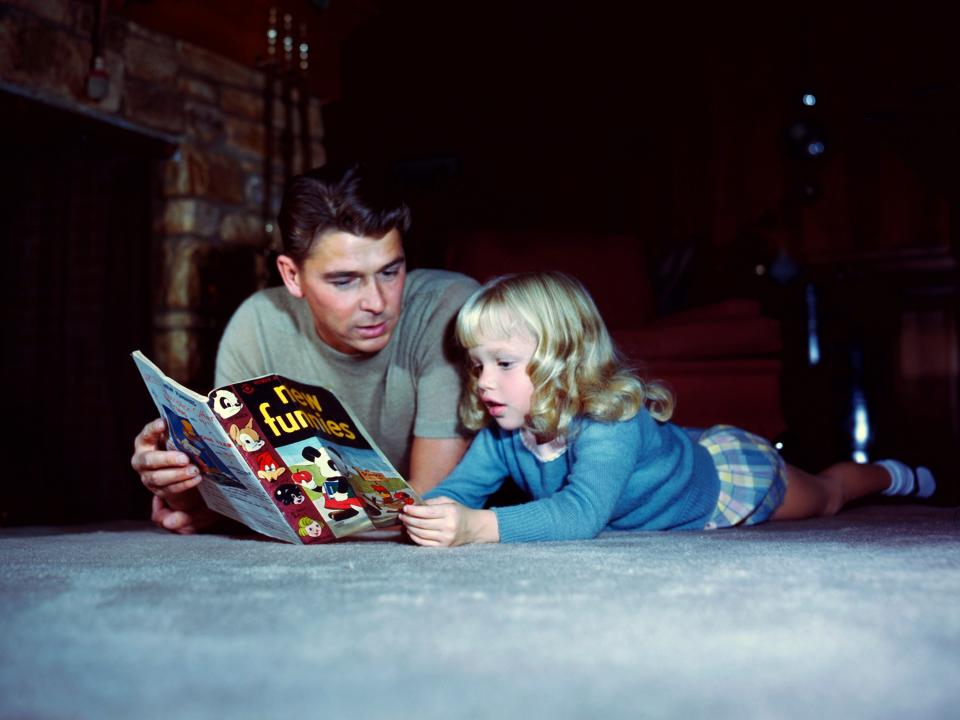 Ronald Reagan reading a magazine with his daughter, Maureen, circa 1945.