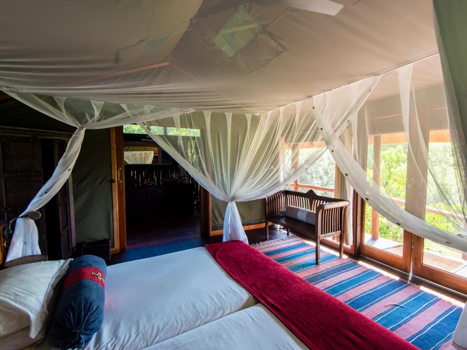 A mosquito net around a bed in a luxurious safari camp tent.