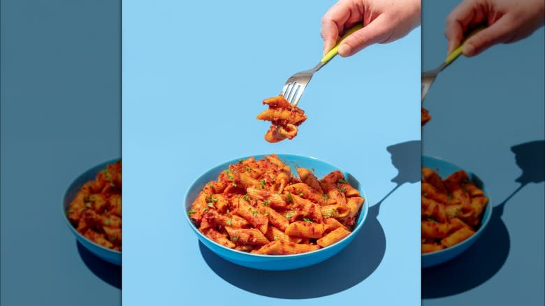 Person eating pasta off of a blue plate