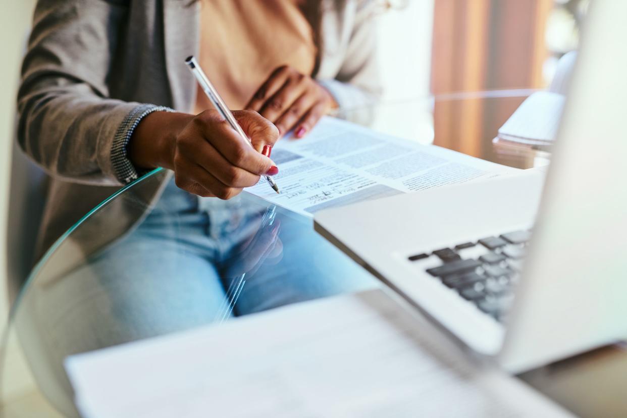 cropped shot of a woman filling out paperwork at home