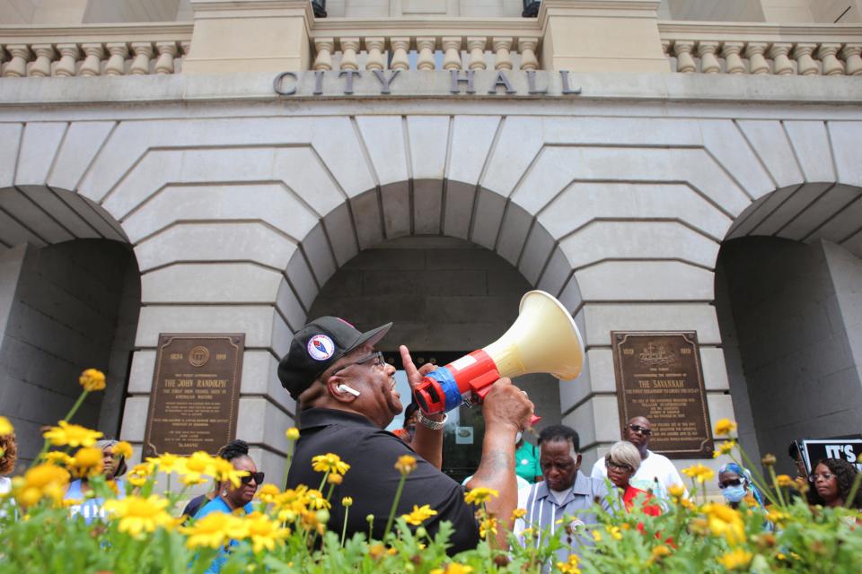 Rev. Dwight Futch leading a prayer outside of city hall surrounded by community members and family of Saudi Arai Lee on Saturday, July 16, 2022