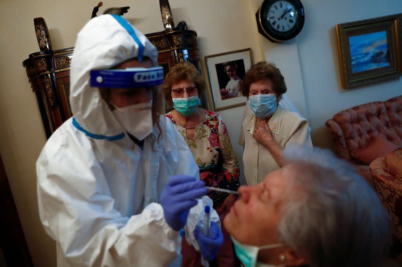 Comunidad de Madrid home care nurse Santamaria performs a PCR test on COVID-19 patient Gutierrez Nogal as her sisters look on in Madrid