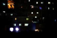 People watch a movie projected on a giant screen, from their windows in the low-income neighborhood of Petare, amid the coronavirus disease (COVID-19) outbreak in Caracas