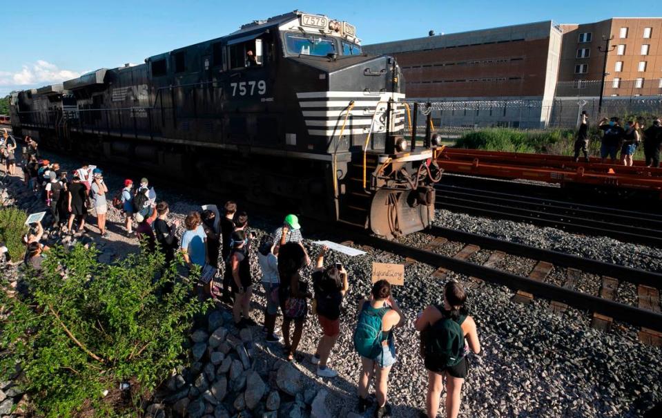 A Norfolk Southern train passes protesters along the tracks at Central Prison on Saturday, June 13, 2020 in Raleigh, N.C. The engineer blew the horn and held a clinched fist out the window of the locomotive as it passed.